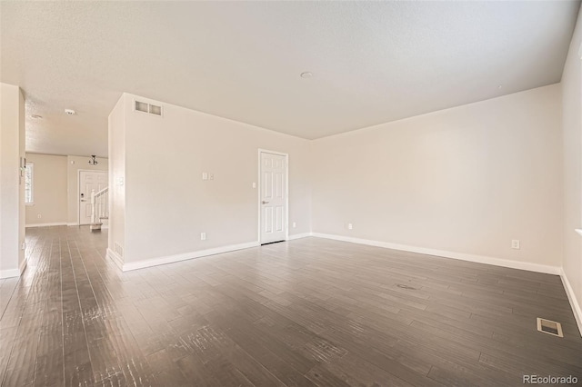 spare room featuring visible vents, dark wood-type flooring, and baseboards