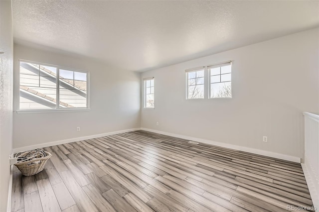 spare room featuring wood finished floors, baseboards, and a textured ceiling