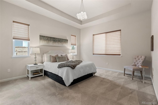 bedroom with carpet, a tray ceiling, and an inviting chandelier