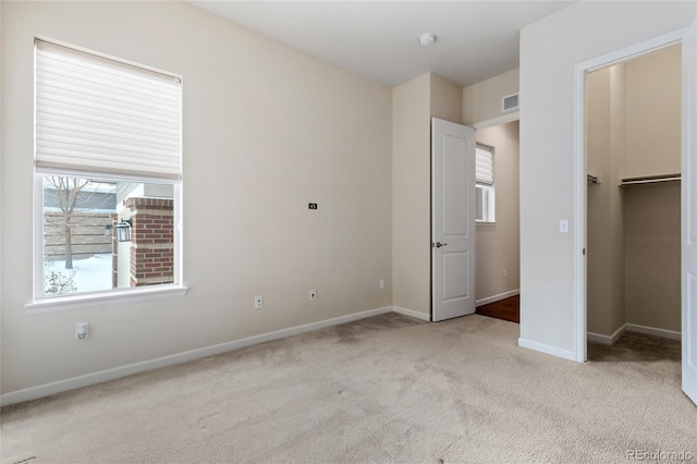 unfurnished bedroom with a closet, a spacious closet, and light carpet