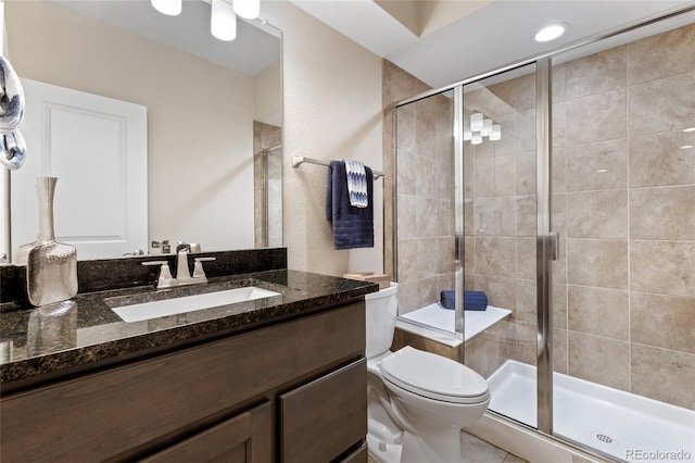 bathroom with toilet, an enclosed shower, and vanity