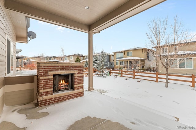 snow covered patio with an outdoor brick fireplace