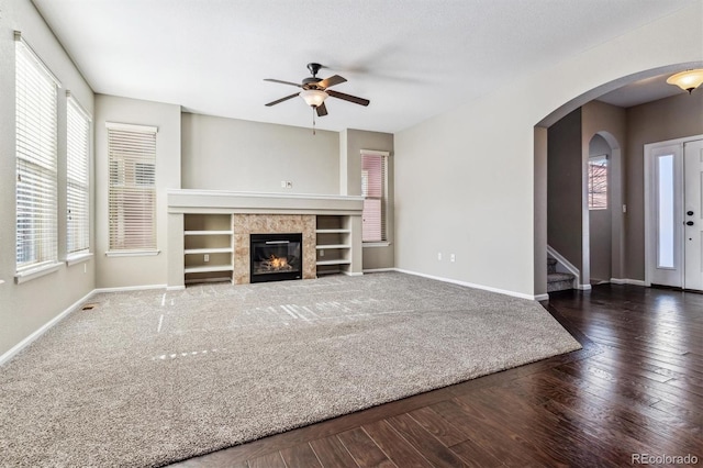 unfurnished living room with ceiling fan, dark hardwood / wood-style flooring, and a tiled fireplace