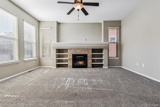 unfurnished living room with ceiling fan, a tiled fireplace, and carpet floors