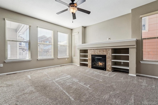 unfurnished living room featuring carpet floors, a healthy amount of sunlight, ceiling fan, and a fireplace