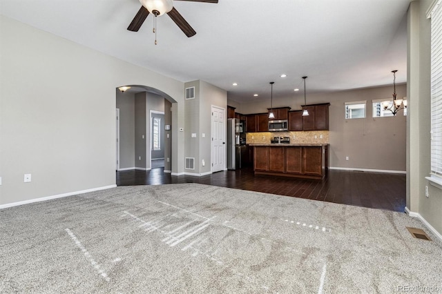 unfurnished living room with dark hardwood / wood-style floors and ceiling fan with notable chandelier