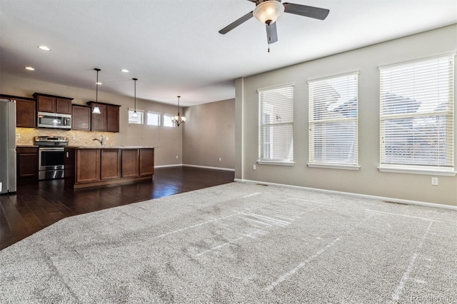 kitchen with sink, ceiling fan with notable chandelier, stainless steel appliances, decorative backsplash, and decorative light fixtures