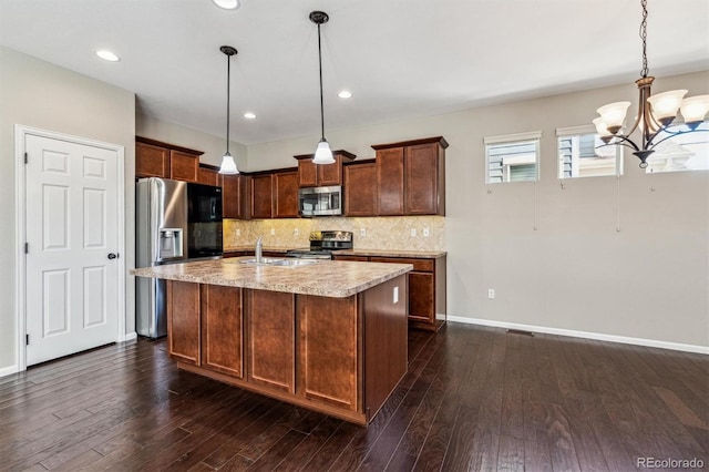 kitchen with tasteful backsplash, decorative light fixtures, stainless steel appliances, and a center island with sink