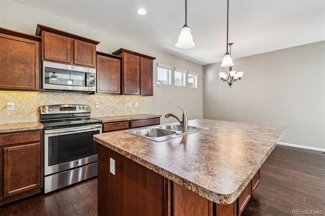 kitchen with dark wood-type flooring, sink, hanging light fixtures, a center island with sink, and appliances with stainless steel finishes