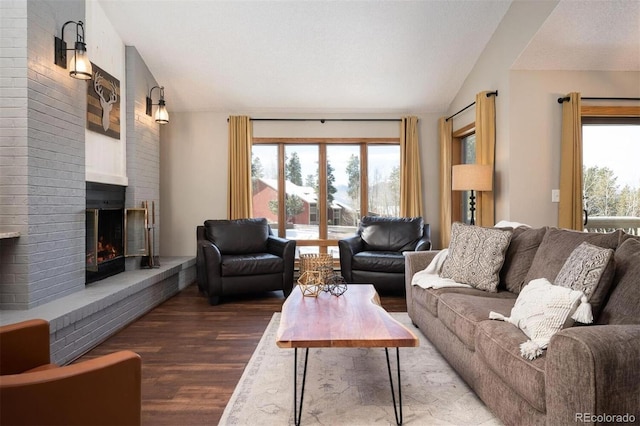 living room with wood-type flooring, vaulted ceiling, and a brick fireplace