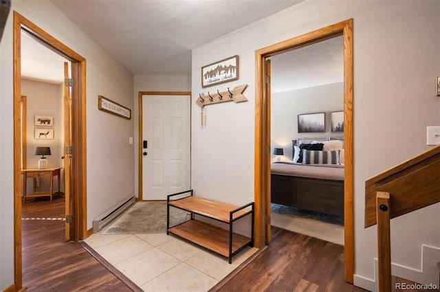 hall with hardwood / wood-style floors, a textured ceiling, and a baseboard heating unit