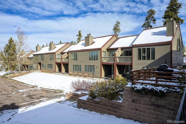 snow covered house featuring a balcony