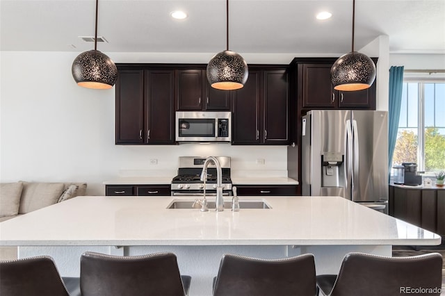 kitchen with pendant lighting, stainless steel appliances, and an island with sink