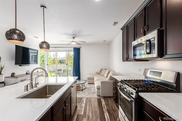 kitchen featuring dark wood-type flooring, dark brown cabinetry, hanging light fixtures, sink, and appliances with stainless steel finishes