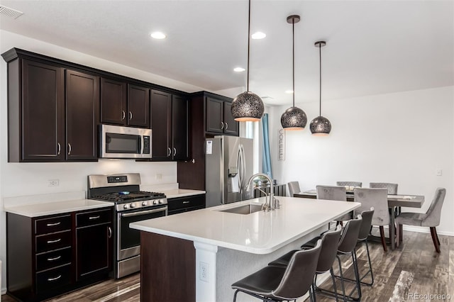 kitchen with sink, appliances with stainless steel finishes, decorative light fixtures, and dark hardwood / wood-style floors