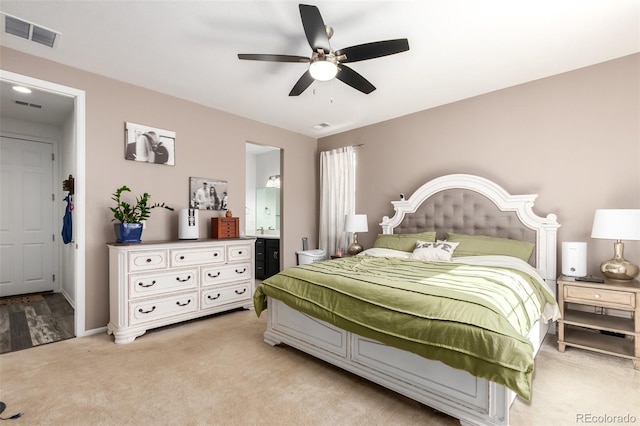 bedroom with ceiling fan, ensuite bath, and light carpet