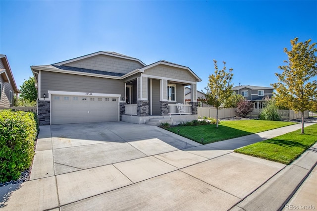 view of front of home featuring a garage, a front yard, and covered porch