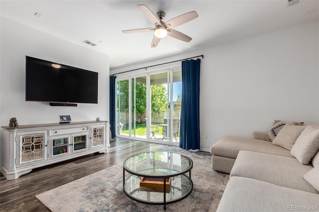 living room featuring dark wood-type flooring and ceiling fan