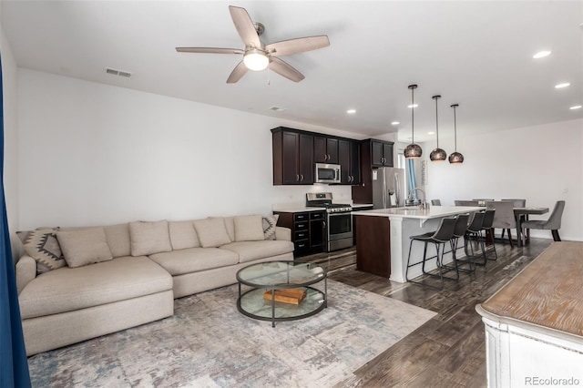 living room featuring ceiling fan, sink, and dark hardwood / wood-style floors