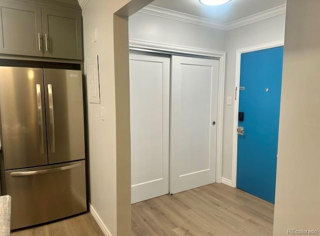 kitchen featuring stainless steel fridge, light hardwood / wood-style floors, and crown molding