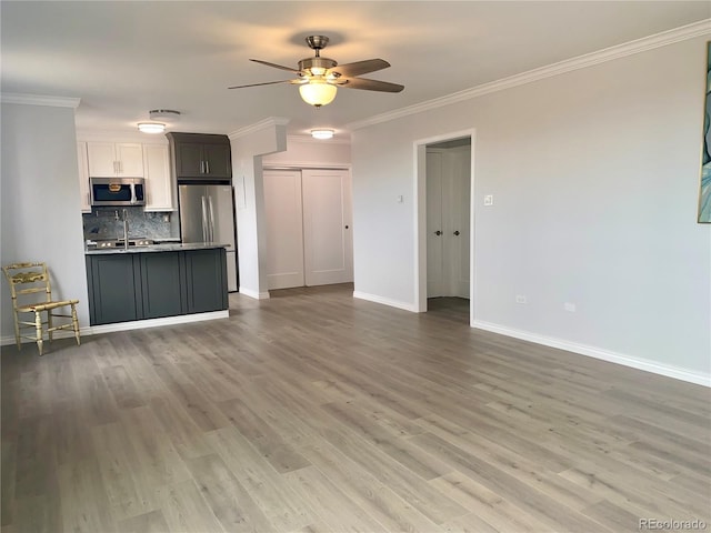 unfurnished living room with crown molding, ceiling fan, sink, and hardwood / wood-style flooring