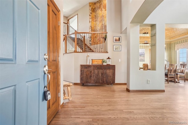 entrance foyer featuring light wood-style flooring, stairway, and baseboards