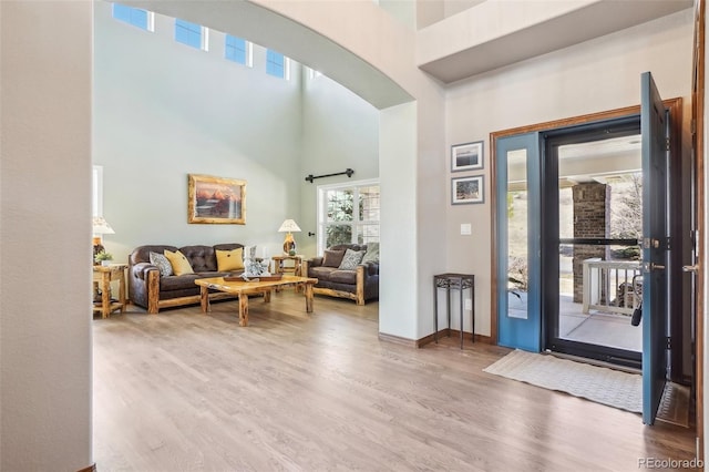 entryway with wood finished floors, a towering ceiling, and baseboards