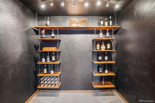 bar featuring a bar, carpet flooring, and track lighting