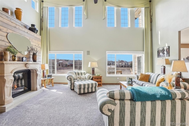 living room with carpet floors, a high ceiling, and a glass covered fireplace