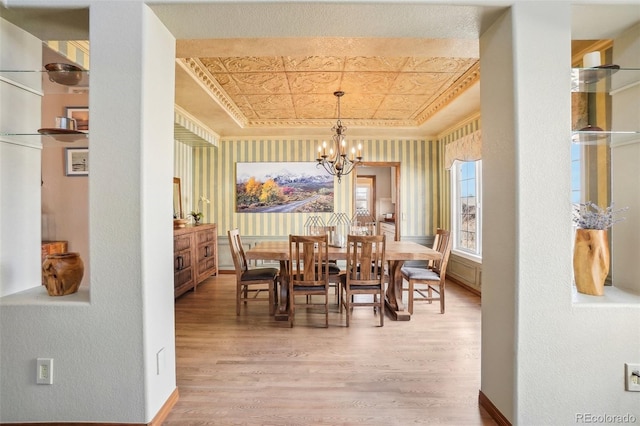 dining room featuring an ornate ceiling, a tray ceiling, a chandelier, light wood-type flooring, and baseboards