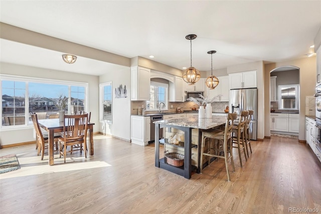 kitchen featuring appliances with stainless steel finishes, arched walkways, white cabinetry, and decorative backsplash