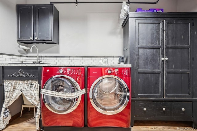 laundry area featuring a sink, cabinet space, washer and clothes dryer, and wood finished floors