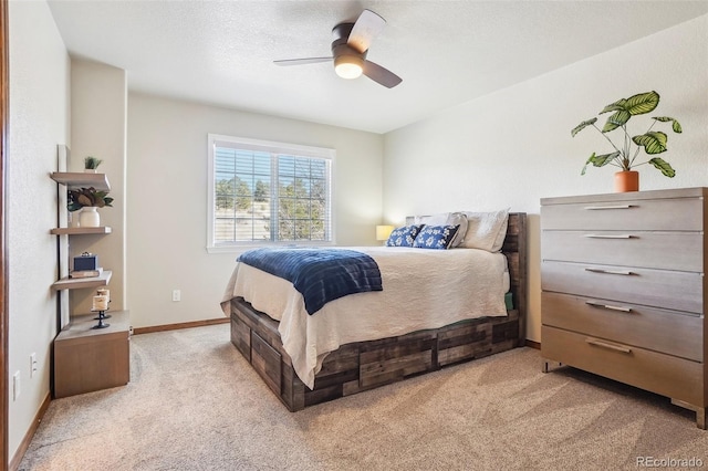 bedroom with a ceiling fan, baseboards, a textured ceiling, and light colored carpet