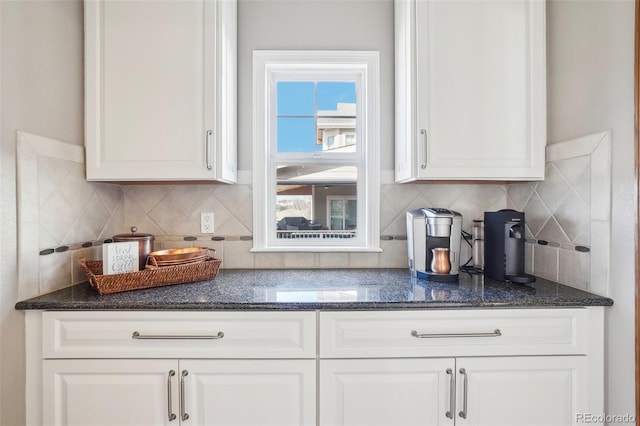 kitchen with dark stone countertops, decorative backsplash, and white cabinets