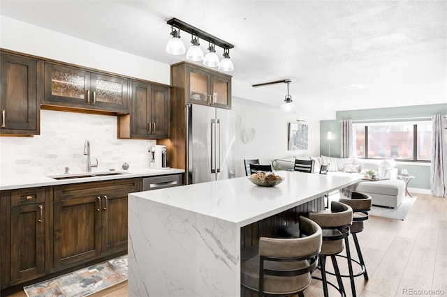 1551 Larimer St Unit 1405, Denver, CO 80202 - kitchen with light wood-style flooring, a sink, stainless steel appliances, decorative backsplash, and dark brown cabinets