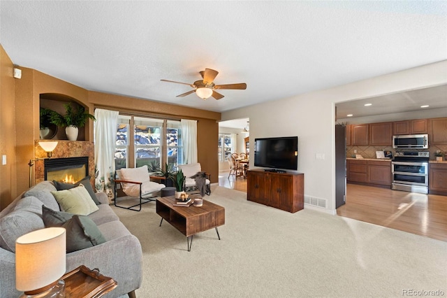 living room featuring ceiling fan, light hardwood / wood-style floors, and a textured ceiling