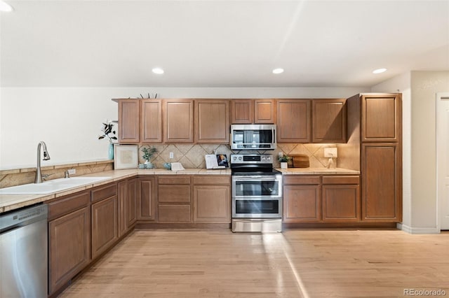 kitchen featuring backsplash, sink, light hardwood / wood-style floors, and appliances with stainless steel finishes