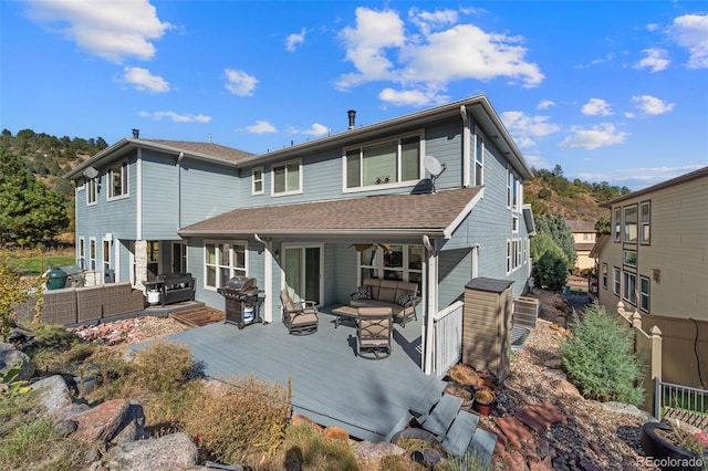 back of property with an outdoor living space and a deck