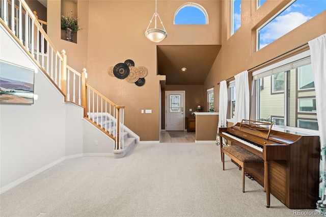 foyer entrance featuring light carpet and a towering ceiling