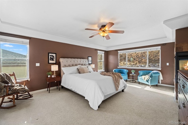 carpeted bedroom with a tiled fireplace and ceiling fan