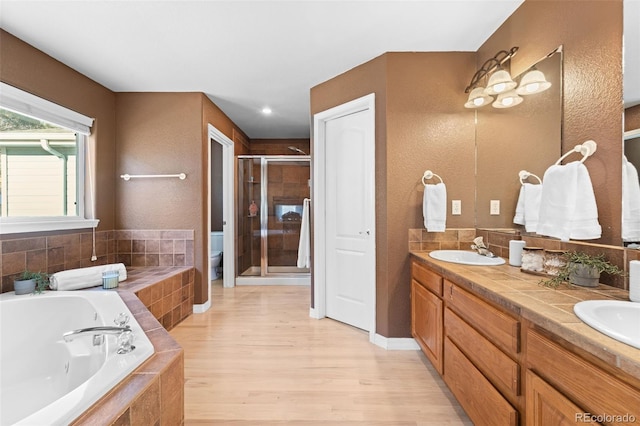 full bathroom with hardwood / wood-style floors, vanity, separate shower and tub, and toilet