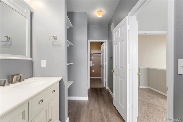 16212 E Geddes Ln Unit 11, Aurora, CO 80016 - bathroom featuring vanity, a spacious closet, baseboards, and wood finished floors