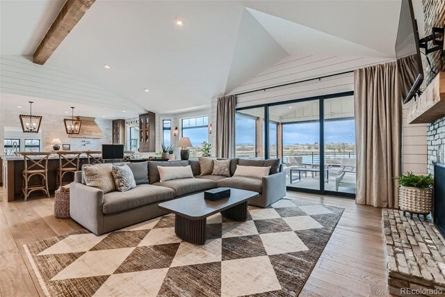 living room featuring light wood-type flooring, a chandelier, high vaulted ceiling, and beamed ceiling