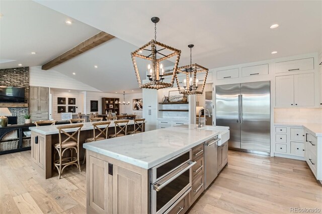 kitchen with appliances with stainless steel finishes, white cabinetry, decorative light fixtures, and a spacious island