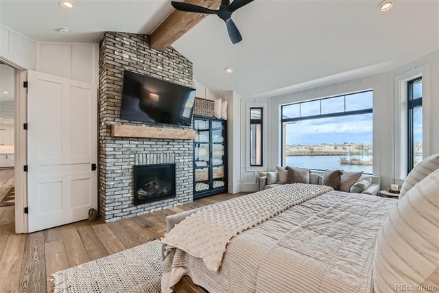 bedroom featuring lofted ceiling with beams, a fireplace, ceiling fan, and hardwood / wood-style flooring