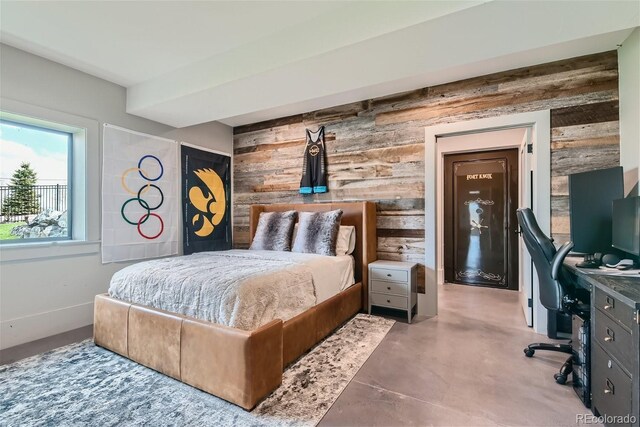 bedroom featuring concrete floors and wood walls