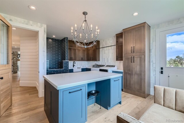 kitchen featuring light wood-type flooring, a chandelier, decorative light fixtures, and a kitchen island