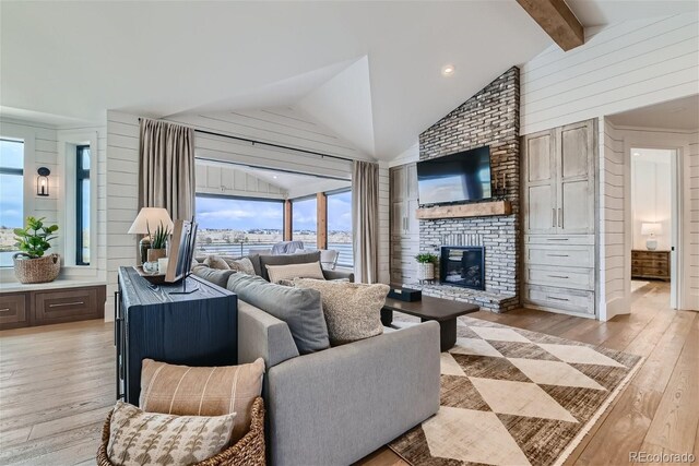 living room featuring light hardwood / wood-style flooring, a brick fireplace, lofted ceiling with beams, and wood walls