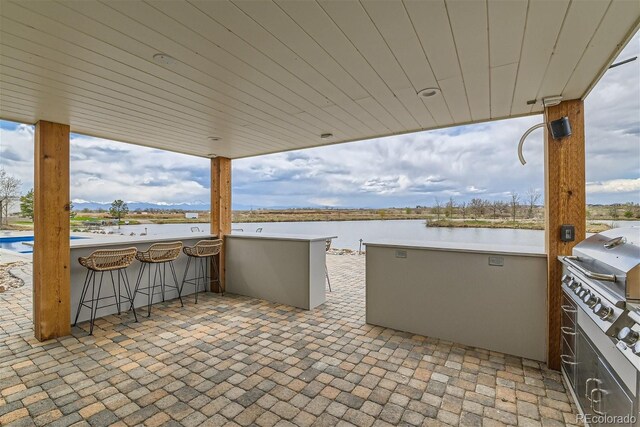 view of patio featuring an outdoor bar, grilling area, area for grilling, and a water view