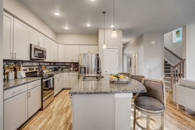 1341 Solitaire St, Colorado Springs, CO 80905 - kitchen featuring decorative backsplash, stainless steel appliances, a center island with sink, stone countertops, and a kitchen breakfast bar